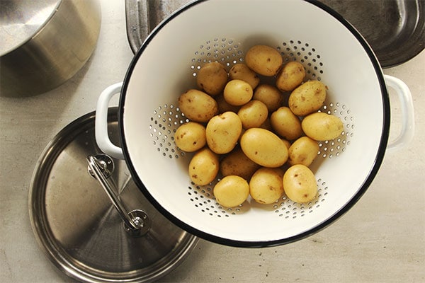 potatoes in white colander with pans in background