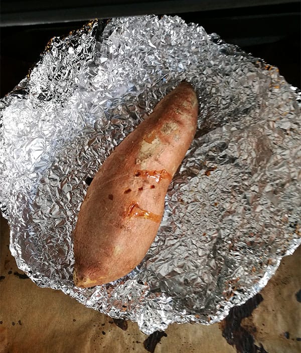 Whole sweet potato with skin is baked on foil.