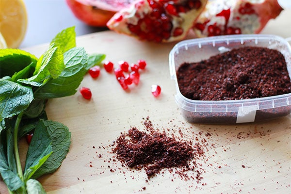 Fresh mint, pomegranate seeds and red sumac on board.