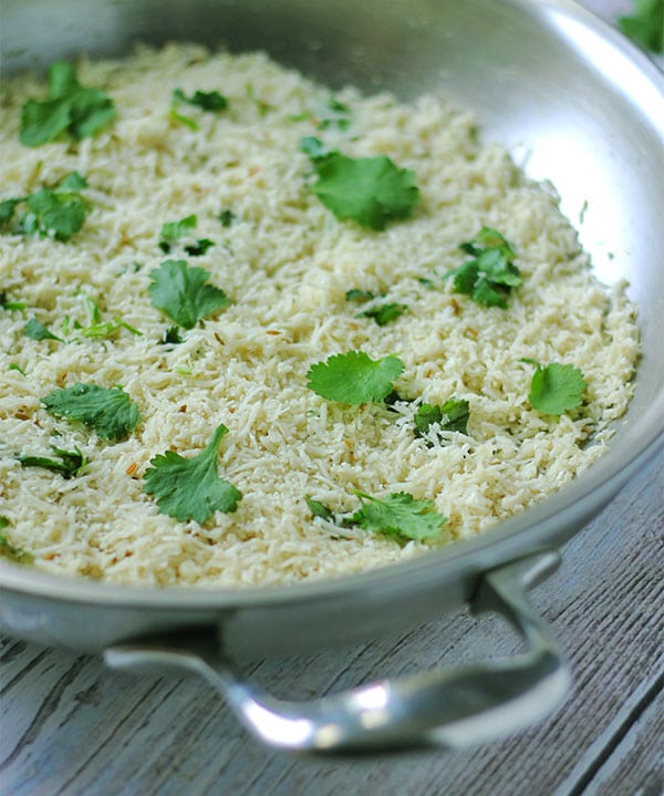 cumin-lime cauliflower rice with fresh coriander (cilantro) in stainless steel pan.