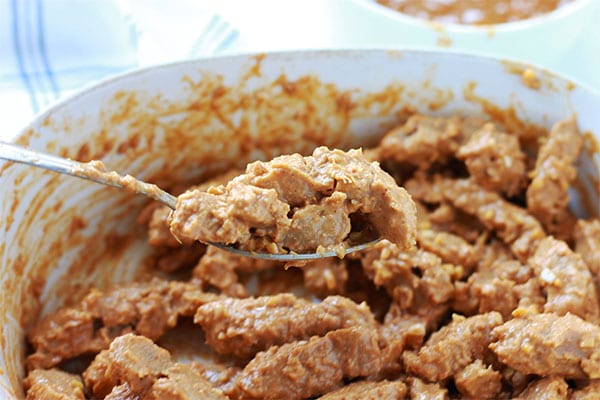 rehydrated soy strips are covered with satay sauce using a spoon.
