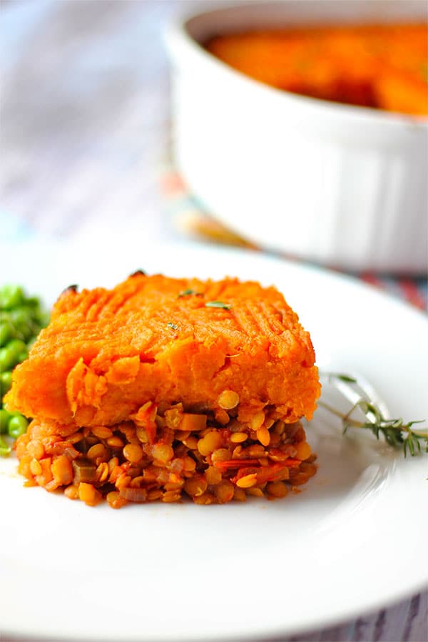 sweet potato Shepherds pie on white plate with white casserole dish of pie in background