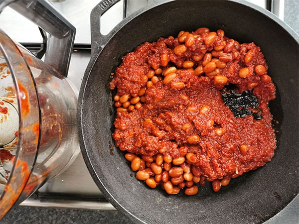 chipotle baked beans in black pot with blender beside it.