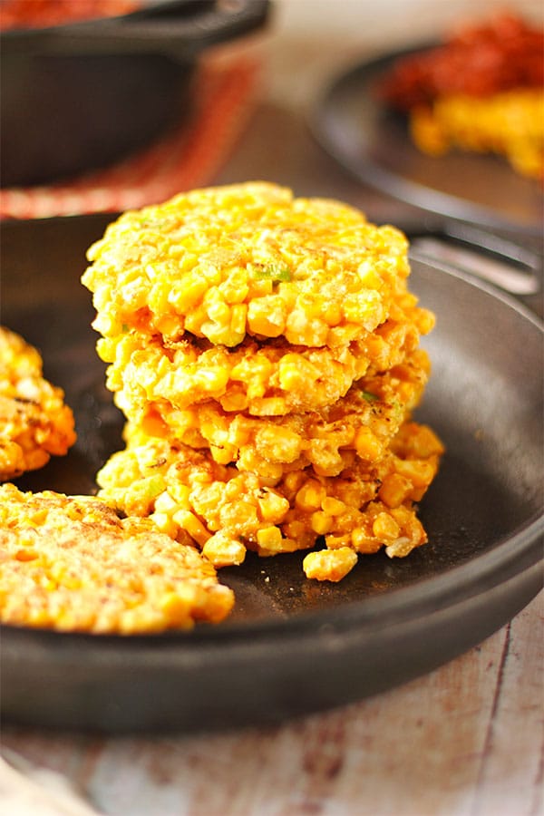 Corn fritters are stacked in a black pan.