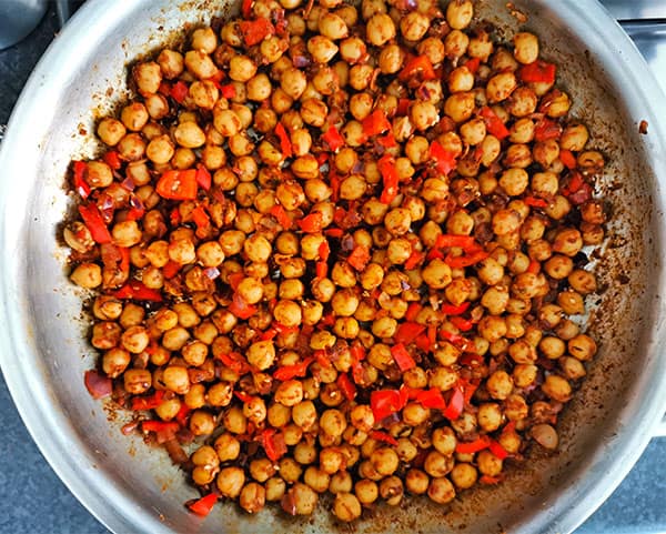 Chickpeas for Middle Eastern chickpea salad are made in a pan with red pepper, onions and spices.