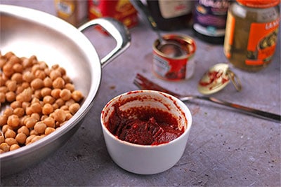 BBQ sauce in small white bowl with tomato paste, tamari, maple syrup, smoked paprika, garlic powder and cumin.
