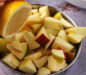 Lemon is squeezed over diced apples.