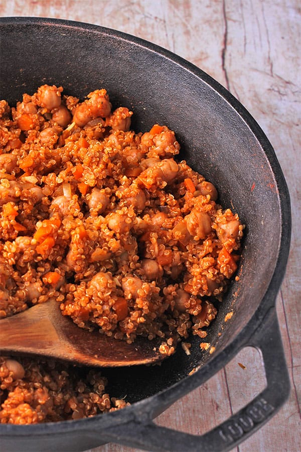 quinoa chickpea pilaf in black cast iron pan with wooden spoon