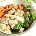 Buffalo chickpea bowl with dressing and spoon on grey board