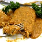 chickpea cutlet with mustard gravy on white plate being cut by fork
