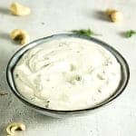cool ranch dressing in blue bowl with cashews and herbs in background