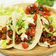3 easy tempeh tacos on wooden plate with blue striped cloth