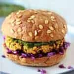 baked samosa burger with red cabbage and coriander mint sauce and bun on blue plate