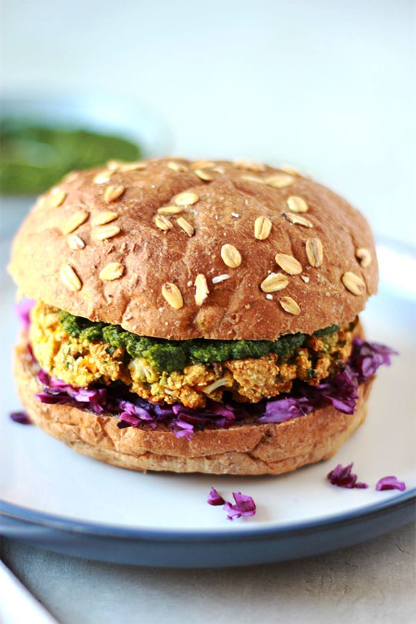 baked samosa burger with red cabbage and coriander mint sauce and bun on blue plate