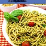 pesto & hemp seed Parmesan over spaghetti with cherry tomatoes in white bowl on red and white cloth.