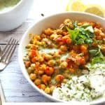 Chana masala with chickpeas topped with coriander coconut cream in white bowl with white rice and text overlay with recipe title, plant-based oil free