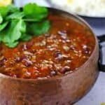kidney bean curry with cilantro in brown metal pot.
