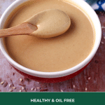 bowl of homemade tahini in red bowl with wooden spoon in bowl full of tahini and text overlay with recipe title
