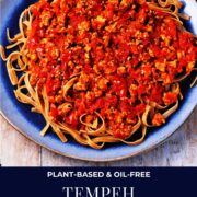 Tempeh Bolognese with wheat tagliatelli pasta on blue plate and text overlay with recipe title.