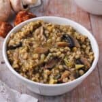 Mushroom barley stew with onions leeks, broccoli and fresh tarragon white bowl