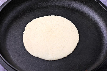 round corn tortilla in cast iron skillet