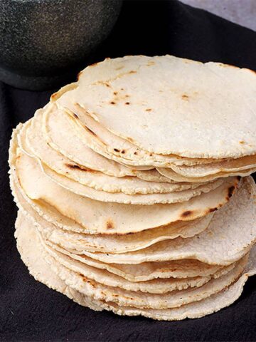 Corn tortillas made with masa harina are stacked on black cloth