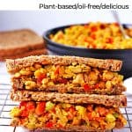 Sandwich filled with curried chickpea salad with red peppers, onions, celery and text overlay with recipe title