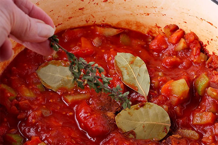 Fresh thyme is added to bay leaves, tomatoes and spices