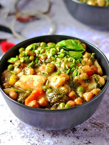 chickpea and vegetable dumpling stew in black bowl