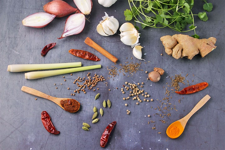 Ingredients for Thai massaman curry paste including dried red chilies, cardamom pods, turmeric, miso paste, cinnamon stick, nutmeg, coriander seeds, lemongrass, ginger, garlic, shallots and cilantro