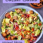 overhead picture of vegan Caesar salad with lettuce, cherry tomatoes, red onion, coconut bacon, croutons and dressing with text overlay of recipe title