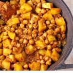 chickpea and potato curry with wooden spoon in black pot