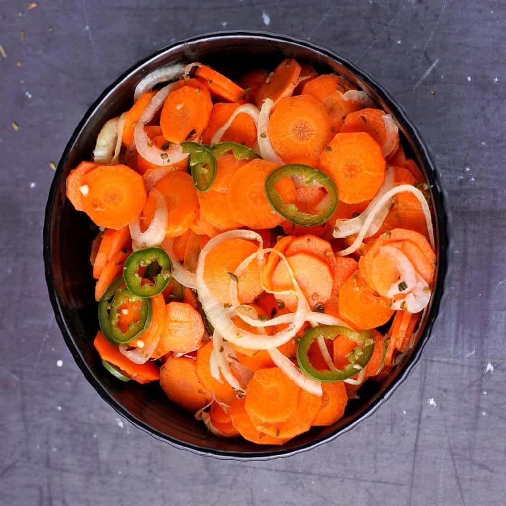 Mexican pickled vegetables (sliced carrots, onions and jalapenos) with dried oregano in black bowl