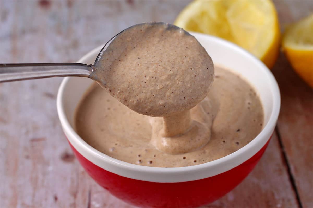 red bowl with spoonful of light brown dressing dripping down