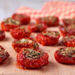 dried tomatoes are with dried herbs are placed on wooden board