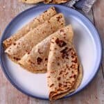 4 whole wheat flatbread are folded on blue plate