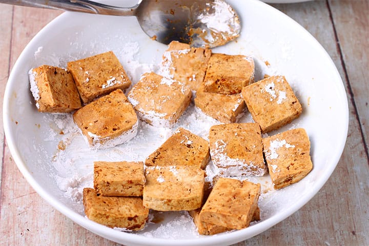 Tofu cubes in white dish are tossed with arrowroot
