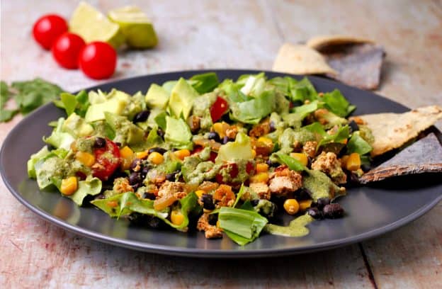 taco salad supreme with chorizo tofu, black beans and corn, lettuce, tomatoes, black olives, cilantro-lime dressing, and tortilla chips
