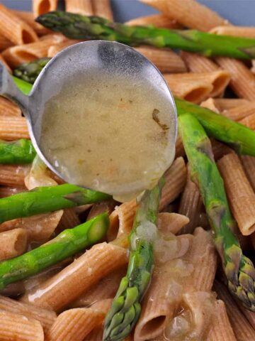 Tarragon sauce is ladled over whole wheat penne pasta and asparagus tips.