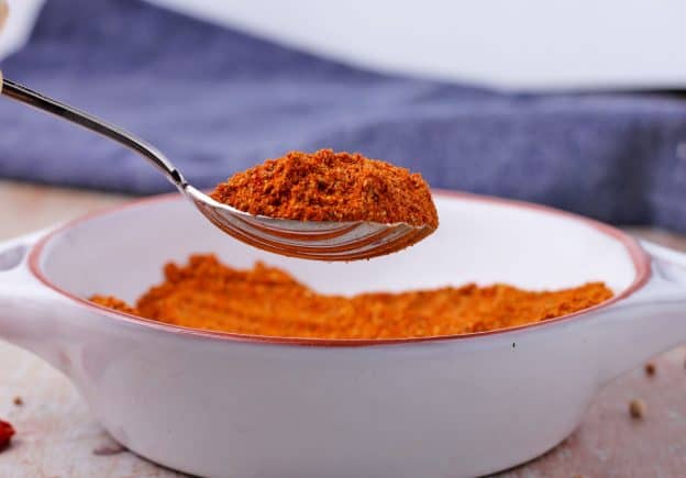 Spoonful of red Ethiopian berbere spice mix and in white bowl