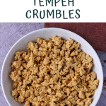 tempeh is crumbled and simmered and placed in a white bowl