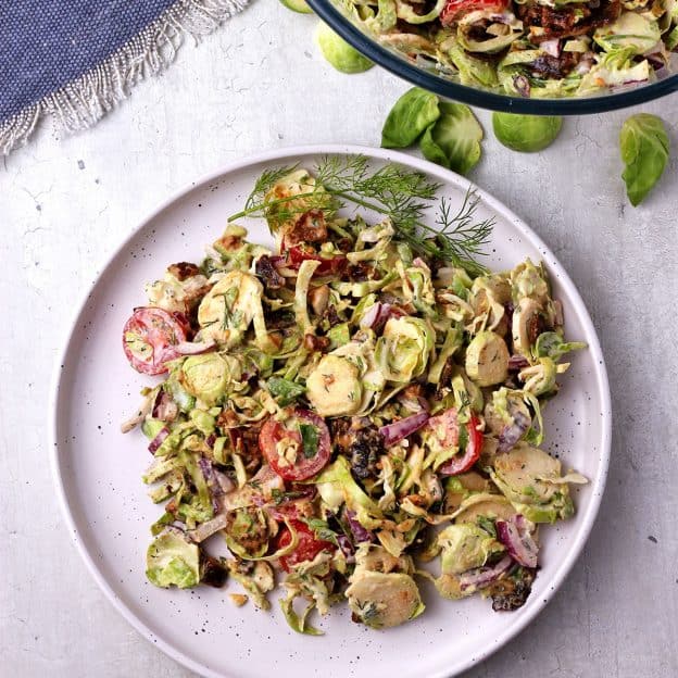 white plate with shaved Brussels sprouts salad