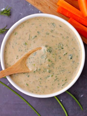 overhead shot of tahini ranch dressing in bowl with small wooden spoon