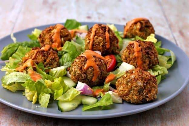 baked veggie balls on salad with lettuce, cucumber, red onions, tomato, and orange dressing.