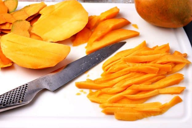 Fresh mango is peeled and cut into strips.