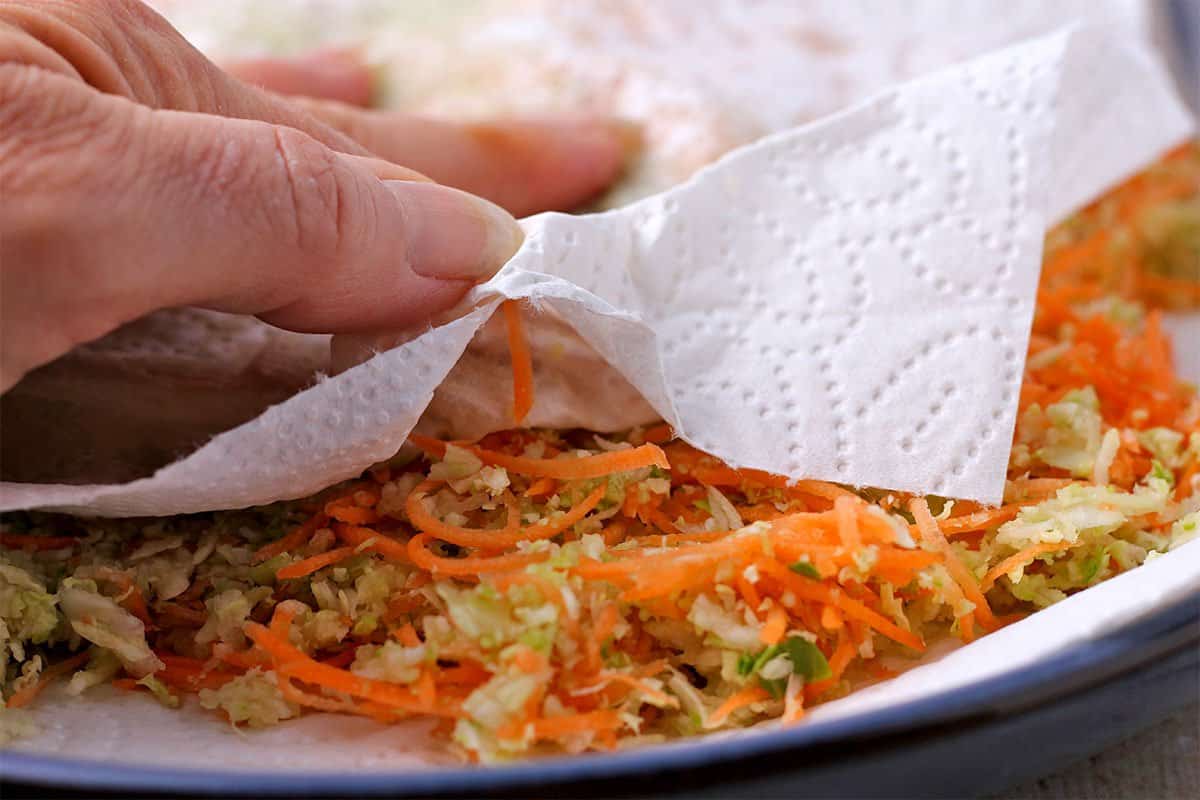 grated carrots, cabbage, and Brussels sprouts are press with a paper towel.