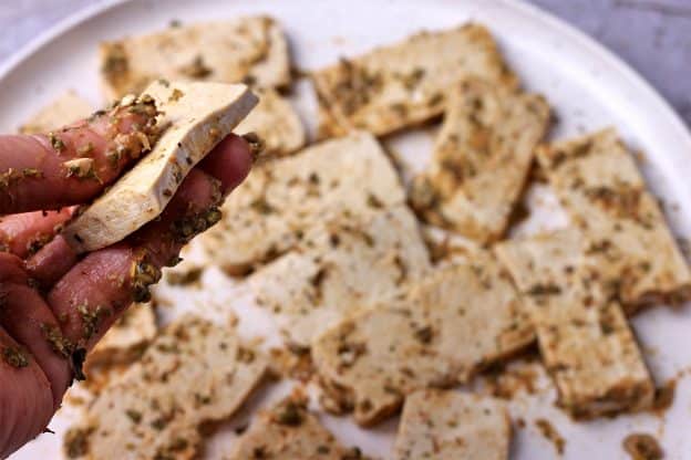 Tofu slices are rubbed with a marinade.