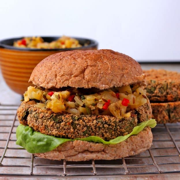 Baked Spinach and potato patties on bun with lettuce and pineapple chutney is placed on a wire rack.
