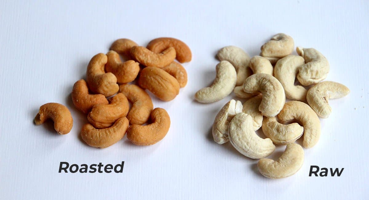 roasted and raw cashews on a blue paper.
