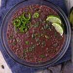 A bowl of refried black beans with sliced jalapenos,